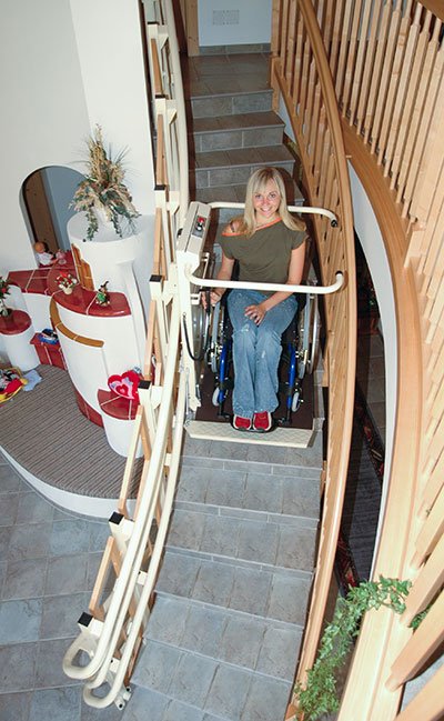 Eine junge Dame benutzt mit ihrem Rollstuhl den Plattformtreppenlift OMEGA im Innenbereich