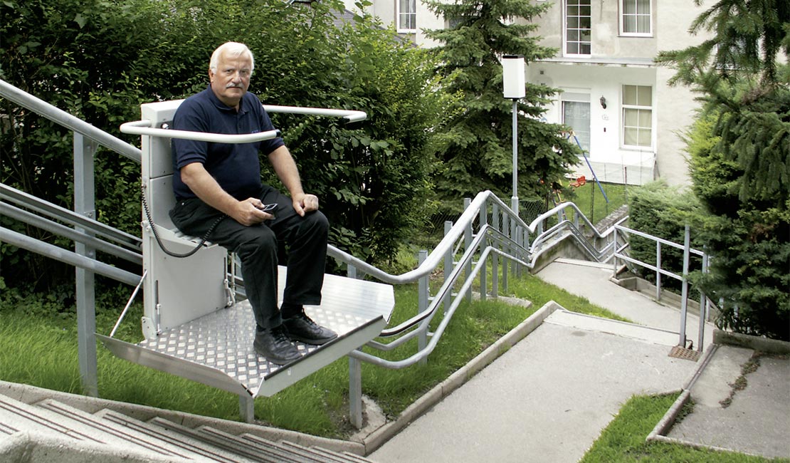 Ein älterer Herr benutzt den Plattformtreppenlift OMEGA im Außenbereich